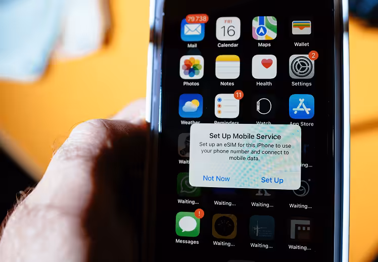 iPhone displaying a pop-up screen titled 'Set Up Mobile Services,' prompting the user to configure an eSIM to use their phone number and connect to mobile data