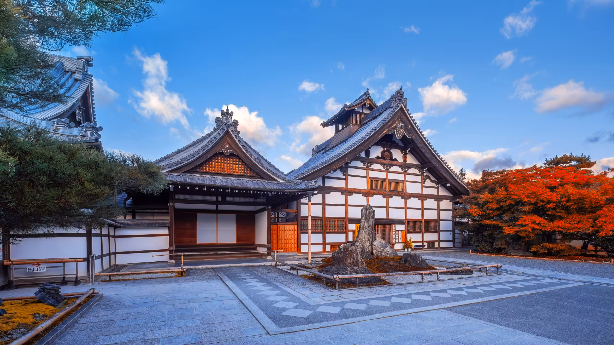 A scenic view of Tenryu-ji Temple in Kyoto during the autumn season, framed by vibrant foliage in shades of red, orange, and yellow