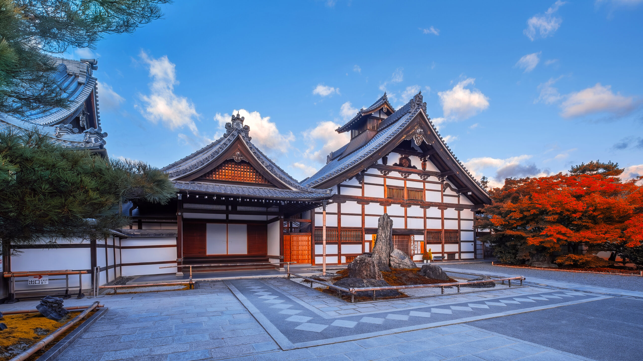 A scenic view of Tenryu-ji Temple in Kyoto during the autumn season, framed by vibrant foliage in shades of red, orange, and yellow