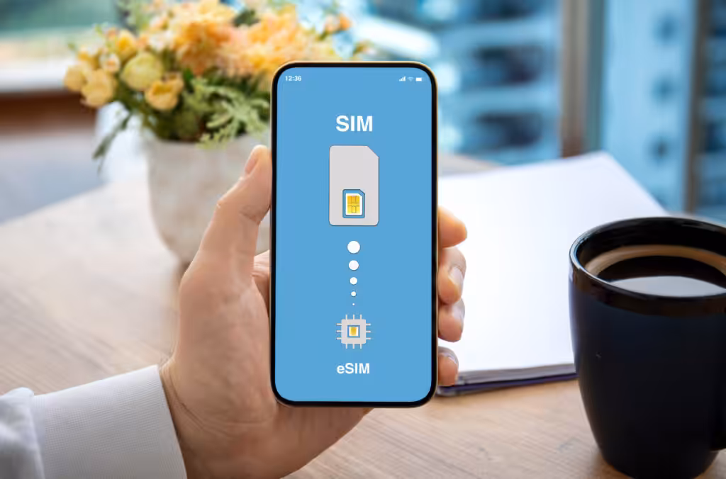 A man is holding a smartphone that displays both the Physical SIM﻿ and eSIM﻿ symbols on its screen, illustrating the coexistence of the two SIM technologies