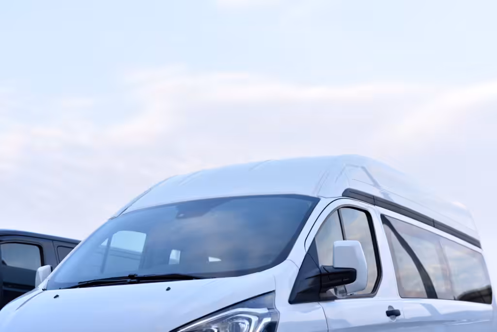 The top part of a white passenger commercial shuttle van is visible at Kansai Airport, captured with a bright sky in the background