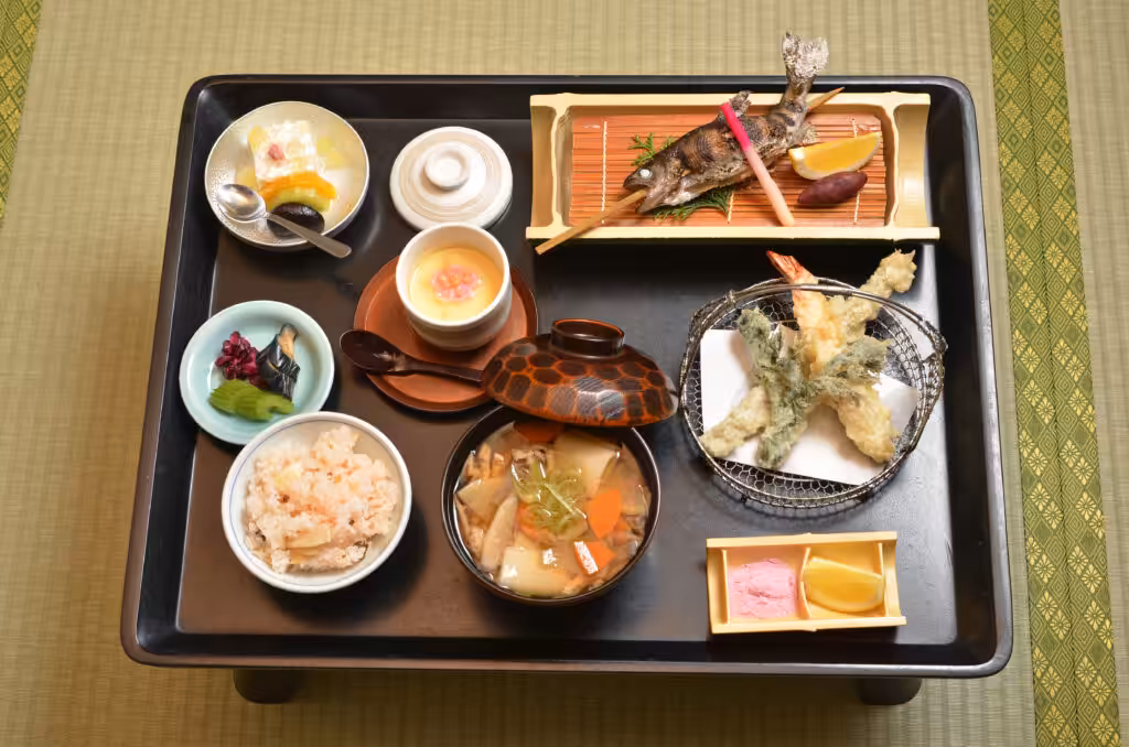 An elegant traditional Japanese kaiseki meal arranged artfully on a low wooden table, featuring multiple small dishes with seasonal ingredients and refined presentation