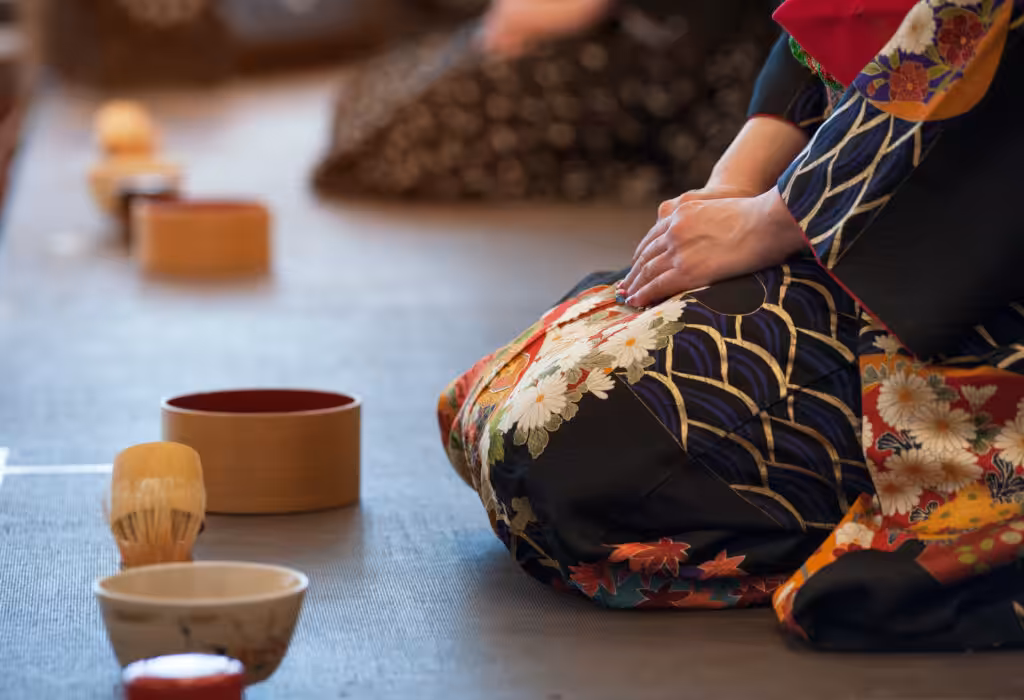 Tourist women dressed in traditional kimonos participate in a Japanese tea ceremony, gracefully preparing and enjoying matcha in a serene setting
