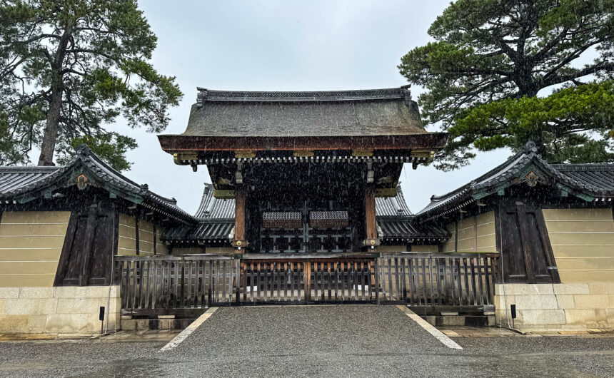 View of the Kyoto Imperial Palace's Kenreimon Gate from Kyoto Gyoen National Garden on a rainy day, with misty atmosphere enveloping the historic wooden architecture
