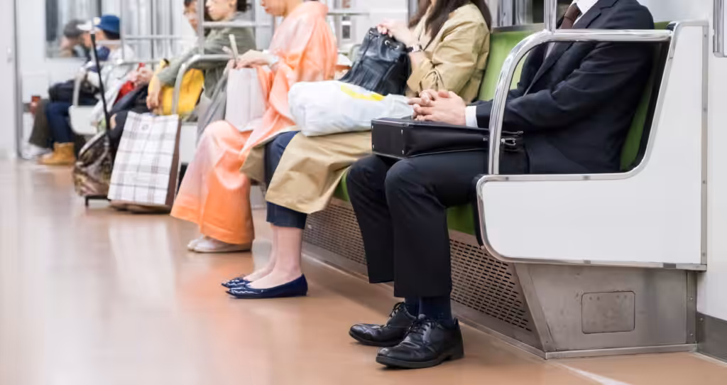 People are sitting quietly on a Japanese metro train, behaving politely and not disturbing anyone around them