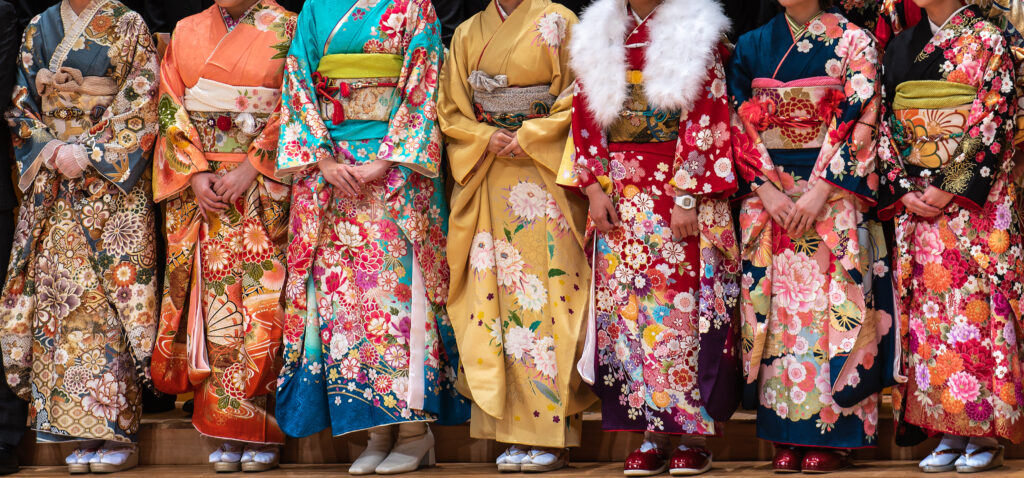A group of women gracefully showcase an array of vibrant, colorful kimonos, each style bursting with traditional Japanese artistry